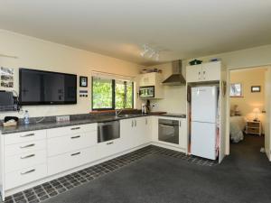a kitchen with white cabinets and a white refrigerator at Whamoori - Waimarama Beach Bach in Waimarama