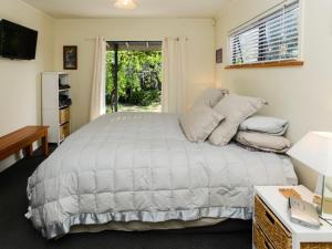 a bedroom with a large bed and a window at Whamoori - Waimarama Beach Bach in Waimarama