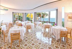 una sala da pranzo con tavoli, sedie e finestre di Hotel San Giorgio Terme a Ischia