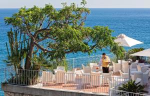a man standing next to a row of chairs and the ocean at Hotel San Giorgio Terme in Ischia
