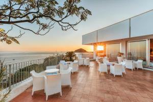 a patio with tables and chairs overlooking the ocean at Hotel San Giorgio Terme in Ischia