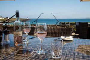 a bottle of wine and three wine glasses on a table at Port Charlotte Hotel in Port Charlotte