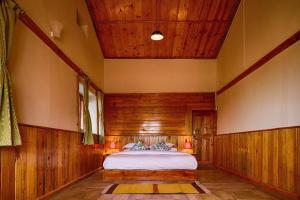 1 dormitorio con 1 cama en una habitación con paredes de madera en Enchanted Hills Farmstay en Mukteswar
