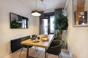 jadalnia z drewnianym stołem i zielonymi krzesłami w obiekcie Marzana by Staynnapartments w mieście Bilbao