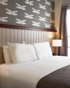 イーストウッドにあるSun Innの白いベッドと蝶の壁が備わるベッドルーム1室が備わります。