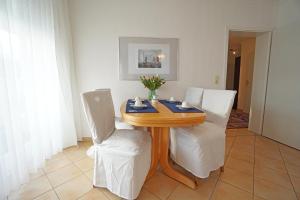 une salle à manger avec une table en bois et des chaises blanches dans l'établissement Villa Madeleine Wohnung 6, à Bansin