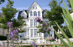 ein weißes Haus mit lila Blumen davor in der Unterkunft Villa Fortuna mit Meerblick in Bansin in Bansin