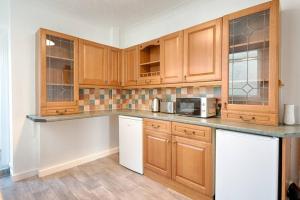 a kitchen with wooden cabinets and a microwave at Great base in Swansea! in Swansea