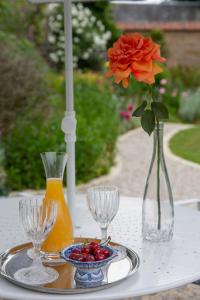 einen Tisch mit einer Vase mit einer Blume und einem Obstteller in der Unterkunft Maison d'hôtes de charme La Rose de Ducey près du Mont Saint Michel in Ducey