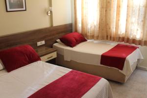 a bedroom with two beds with red and white sheets at Dove Apart Hotel in Fethiye