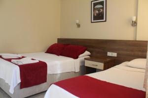 a hotel room with two beds with red and white sheets at Dove Apart Hotel in Fethiye
