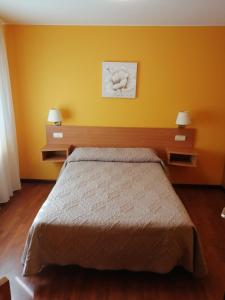 1 dormitorio con cama y pared amarilla en Pensión Teyma, en Ponteceso