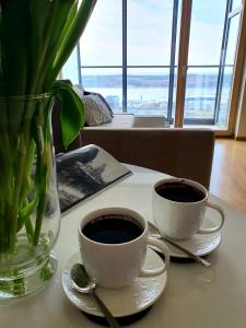 two cups of coffee on a table with a vase at Sea View Apartment in Klaipėda in Klaipėda