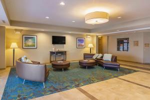 Candlewood Suites - Pensacola - University Area, an IHG Hotel في بينساكولا: لوبي فيه كنب وكراسي وتلفزيون بشاشة مسطحة