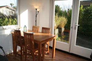 een houten tafel en stoelen in een kamer met een raam bij Rekerlanden 257 in Schoorldam