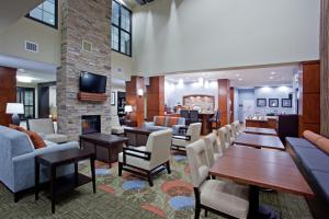 a living room with chairs and tables and a fireplace at Staybridge Suites Houston Stafford - Sugar Land by IHG in Stafford