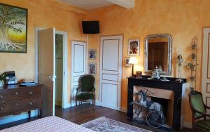 1 dormitorio con chimenea, 1 cama y espejo en Domaine de Las Planques, en Vaudreuille