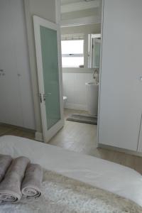 a white bedroom with a bathroom with a tub and a sink at Beach Club Unit 207 in Mossel Bay