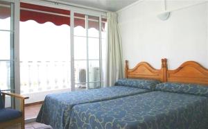 a bedroom with a bed with a blue comforter at Hotel Betania in Benalmádena