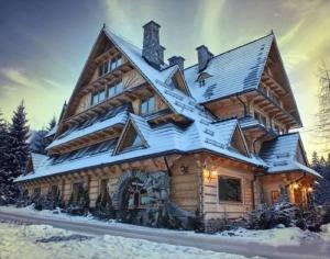 domek z bali i śniegiem na dachu w obiekcie Apartament Harnasiowa Grota w mieście Kościelisko