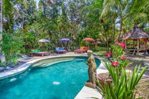a swimming pool with a statue in the middle of a yard at Swasti Eco Cottages in Ubud