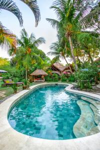 a swimming pool in front of a resort with palm trees at Swasti Eco Cottages in Ubud