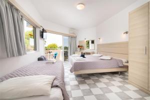 two beds in a bedroom with a checkered floor at Sabina Hotel in Theologos