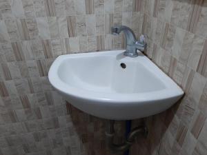 lavabo blanco con grifo en el baño en Clark-Pad Inn, Angeles City, en Ángeles