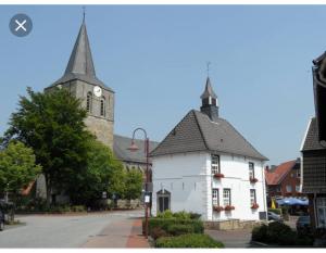 a white building with a clock tower and a church at Ferienhaus uelsen in Uelsen