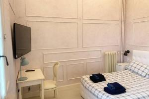een slaapkamer met een bed, een bureau en een televisie bij Suite Nico Bologna Centro in Bologna