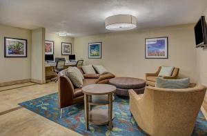 Candlewood Suites Louisville Airport, an IHG Hotel في لويزفيل: غرفة معيشة مع أريكة وكراسي وطاولة
