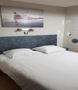 - une chambre avec un lit blanc et une photo sur le mur dans l'établissement Studio Naturiste "SUNSHINE" Héliopolis FG 14, au Cap d'Agde