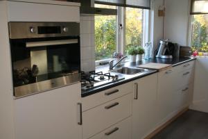 a kitchen with white cabinets and a stove top oven at Rekerlanden 195 in Schoorldam