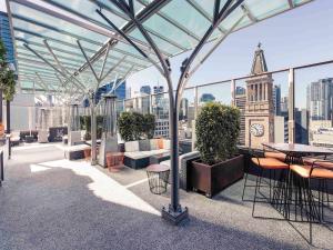 a rooftop patio with tables and chairs on a building at Mercure Brisbane King George Square in Brisbane