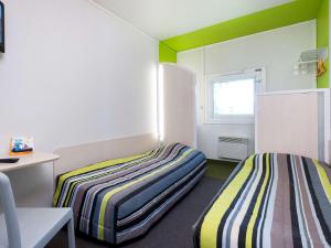 2 camas en una habitación con paredes verdes y blancas en hotelF1 Sens Nord, en Sens