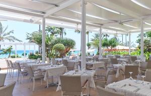 a restaurant with white tables and chairs and the ocean at Sunrise Beach Hotel in Protaras
