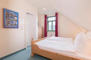 a bedroom with a bed with white sheets and a window at Ferienhaussiedlung Strandperlen Küstenhof 1d (Typ IV) in Wustrow
