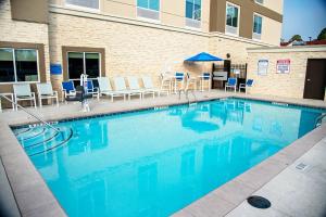 una grande piscina con sedie e tavolo di Holiday Inn & Suites - Savannah Airport - Pooler, an IHG Hotel a Savannah