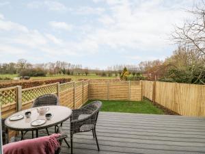 a patio with a table and chairs and a fence at Beechnut Cottage in Tewkesbury
