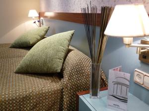 a bed with two pillows and a lamp on a table at Hotel Jardín de Aranjuez in Aranjuez