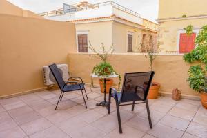 2 Stühle und ein Tisch auf der Terrasse in der Unterkunft Alegria Pension in Chania