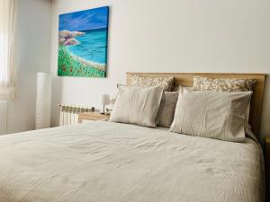 a bedroom with a white bed with a painting on the wall at Casa 1627 in Blanes