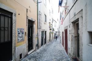 un callejón en un viejo pueblo con una persona caminando por él en Lisbon Alfama S. Pedro Typical, en Lisboa