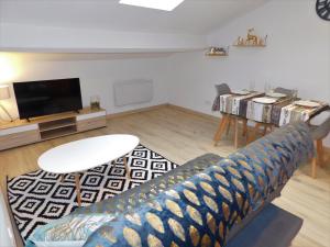 uma sala de estar com um sofá e uma televisão de ecrã plano em YES HOME em Lamalou-les-Bains