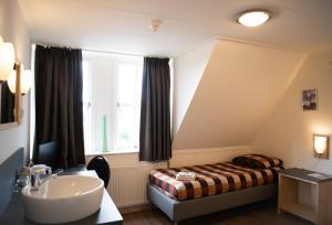 een badkamer met een wastafel, een bed en een raam bij Herberg de Zwaan Hedel in Hedel