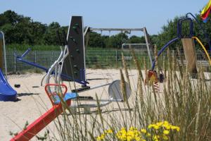een speeltuin met een wip en schommels in het zand bij Sandy 36 in Callantsoog