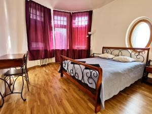 a bedroom with a bed and a desk and red curtains at Brivibas Center Apartments in Riga