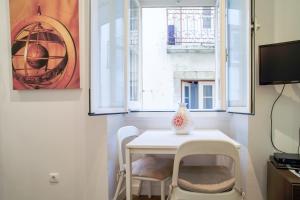 una pequeña mesa blanca y sillas en una habitación con ventanas en Lisbon Alfama S. Pedro Typical, en Lisboa