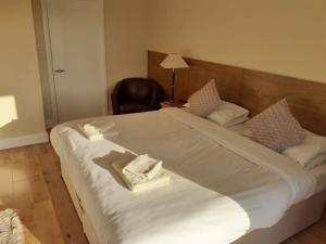 a large white bed in a room with a chair at The Bear Inn and Burwash Motel in Burwash