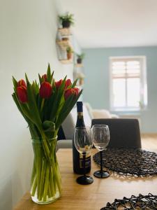 una mesa con una botella de vino y un jarrón de flores en Apartament Bankowa en Jelenia Góra